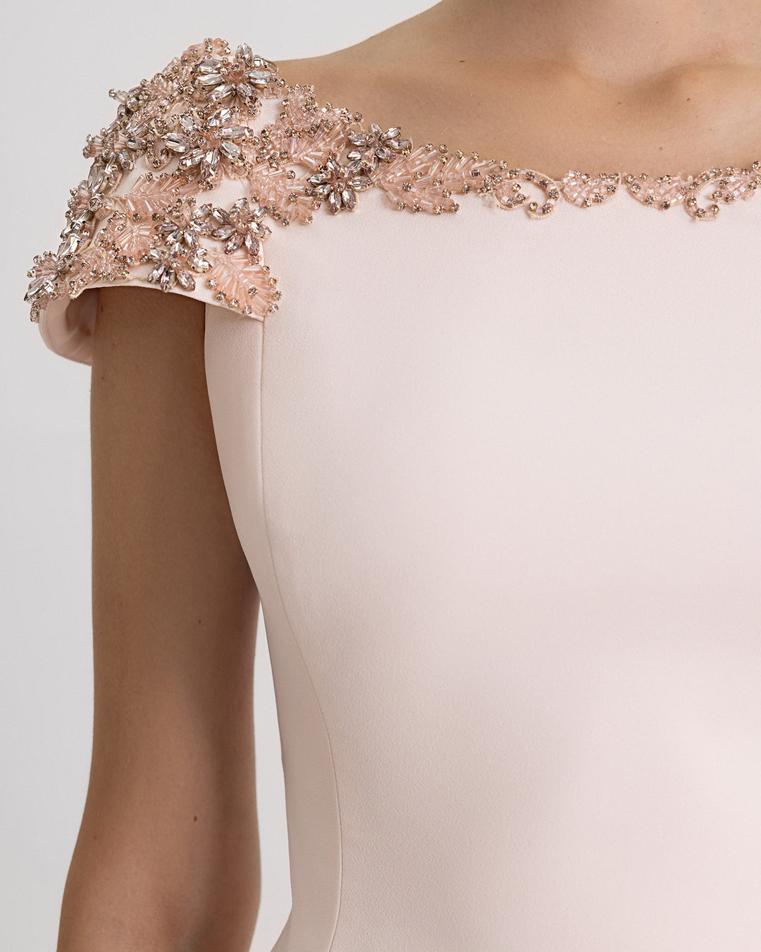 A close-up of an evening dress in light pink with structured beaded shoulders.