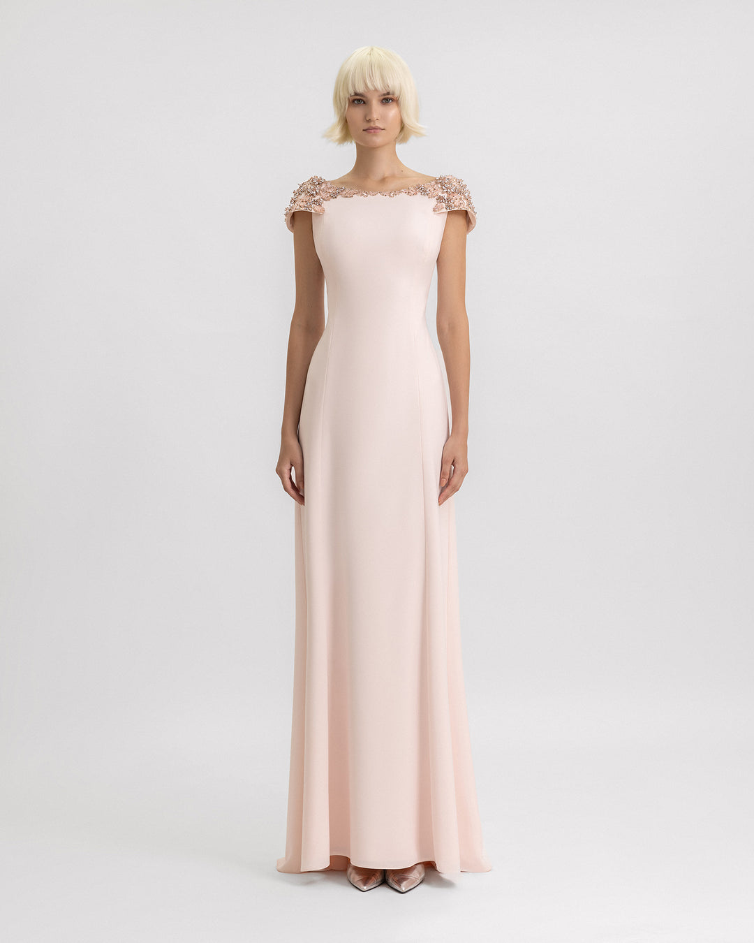 A long evening dress in light pink with structured beaded shoulders.