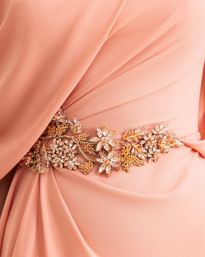 A close-up of a coral evening dress with beadings on the waistline.