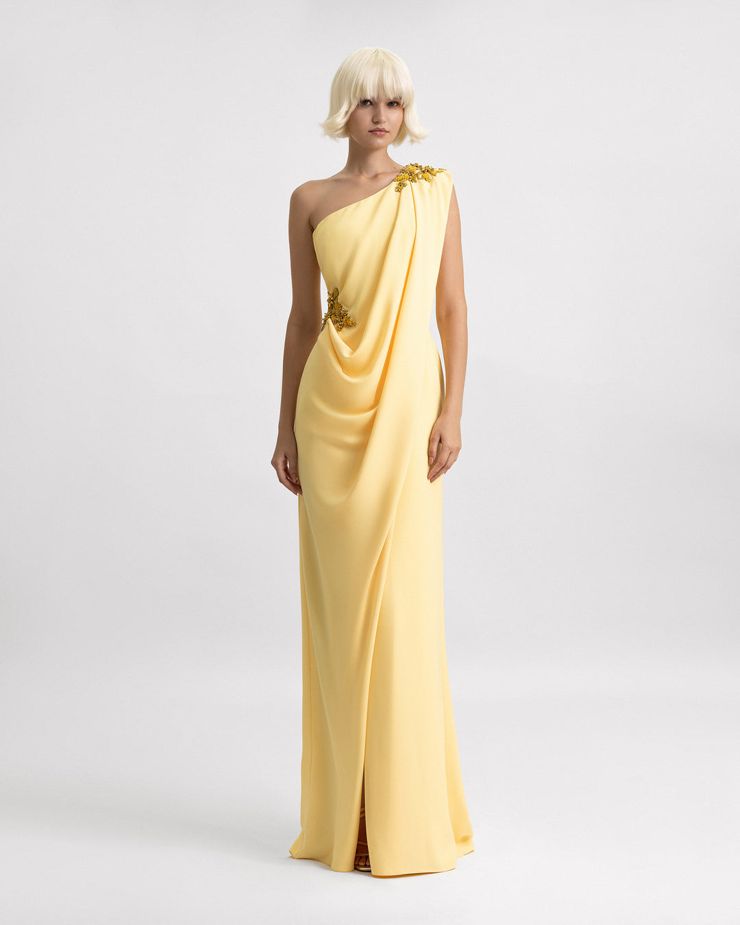 A one-shoulder draped yellow evening dress with beading details on the shoulder and the waist.