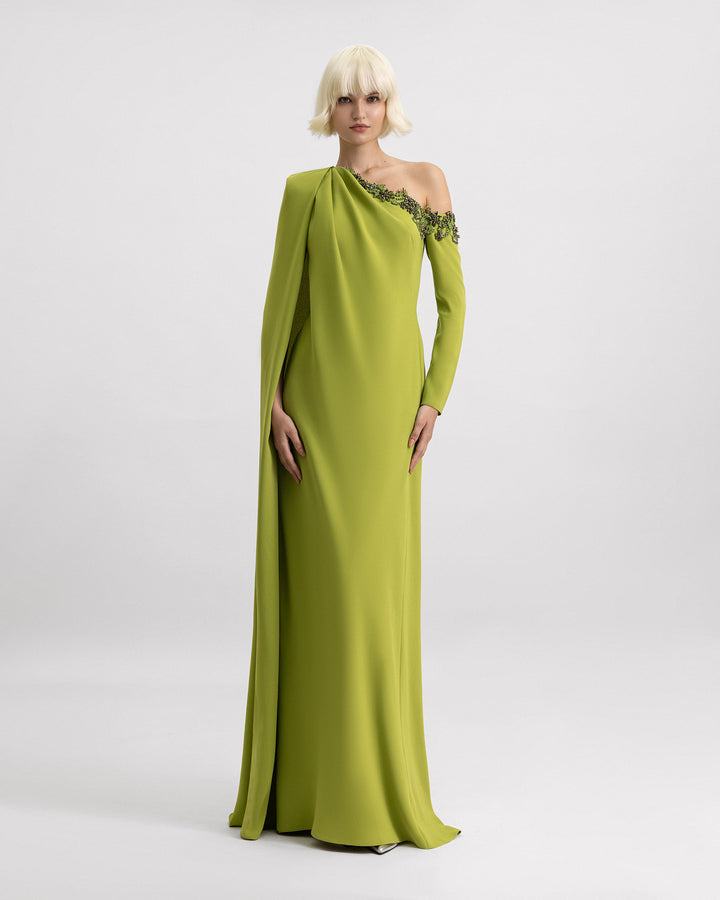 A one-shoulder green evening dress with beadings on the neckline and a cape-like sleeve.
