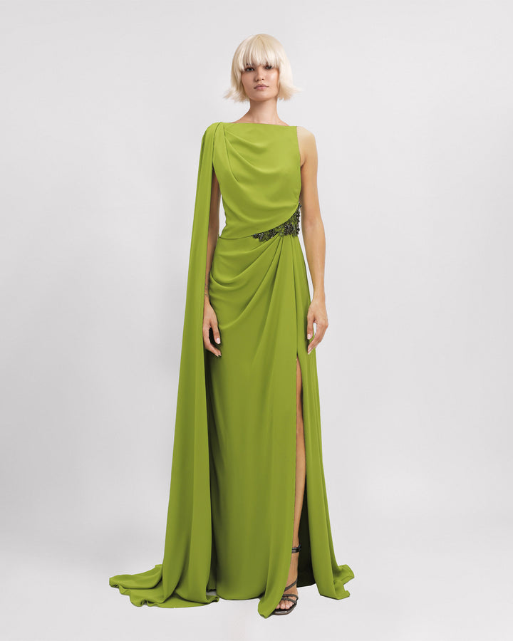 An asymmetrical neckline evening dress with beadings on the waistline, a cape-like sleeve, and a slit on the side.