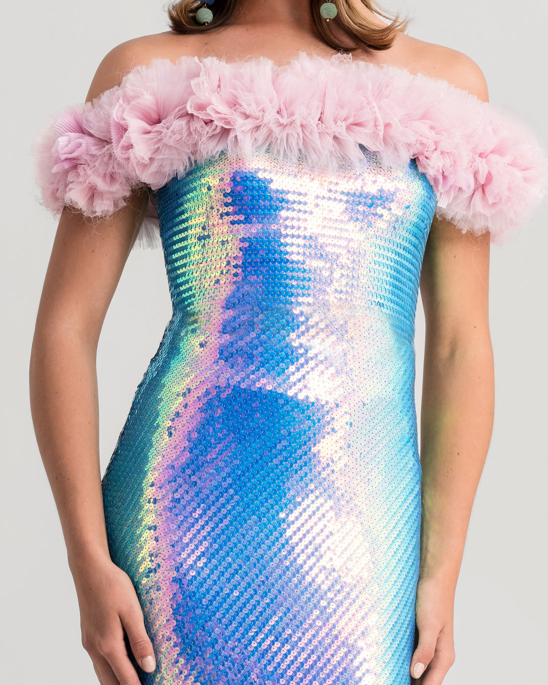 A close-up of a sequined slim-cut evening dress in aqua blue with a pink rushed tulle on the neckline.