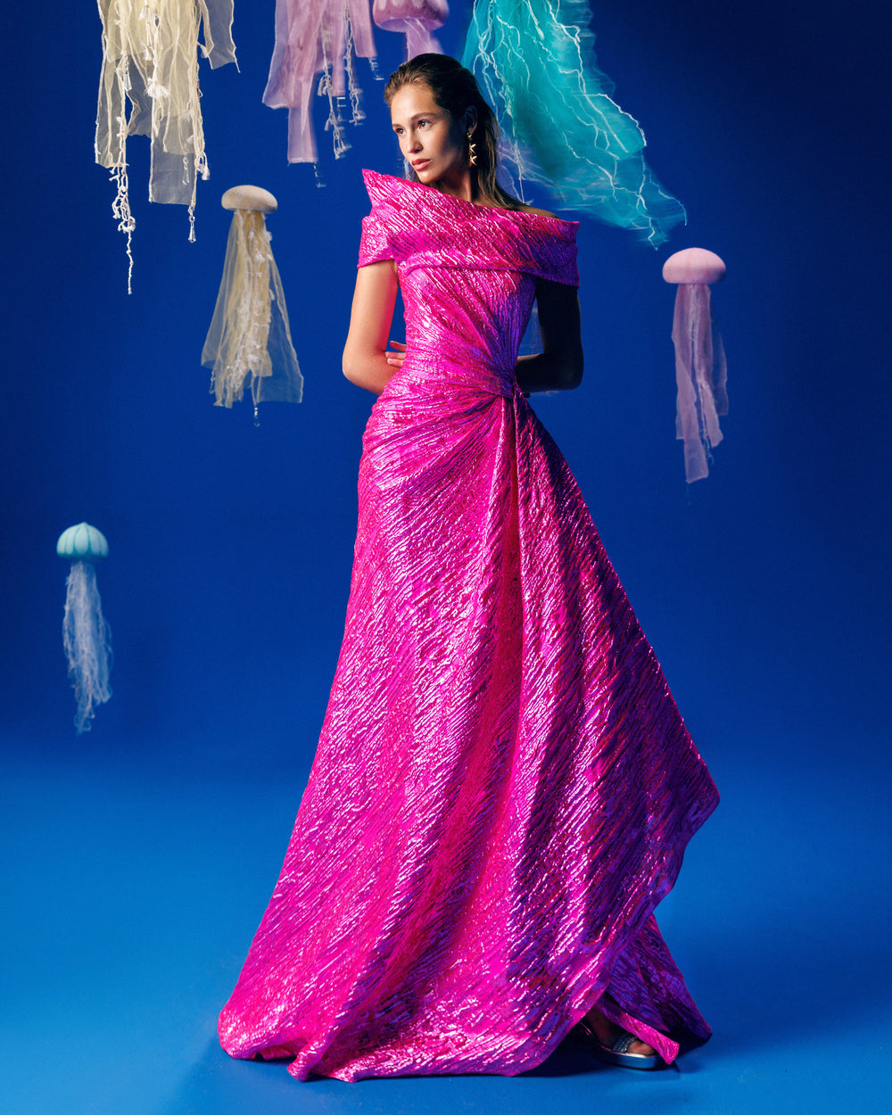 An asymmetrical neckline, off-the-shoulders fuchsia evening dress with a draped waist.