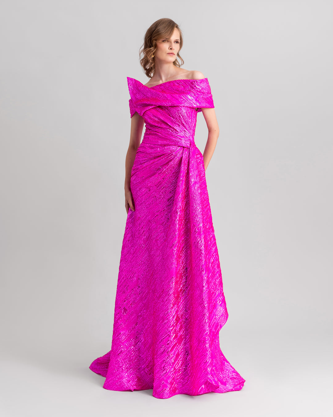 An asymmetrical neckline, off-the-shoulders fuchsia evening dress with a draped waist.