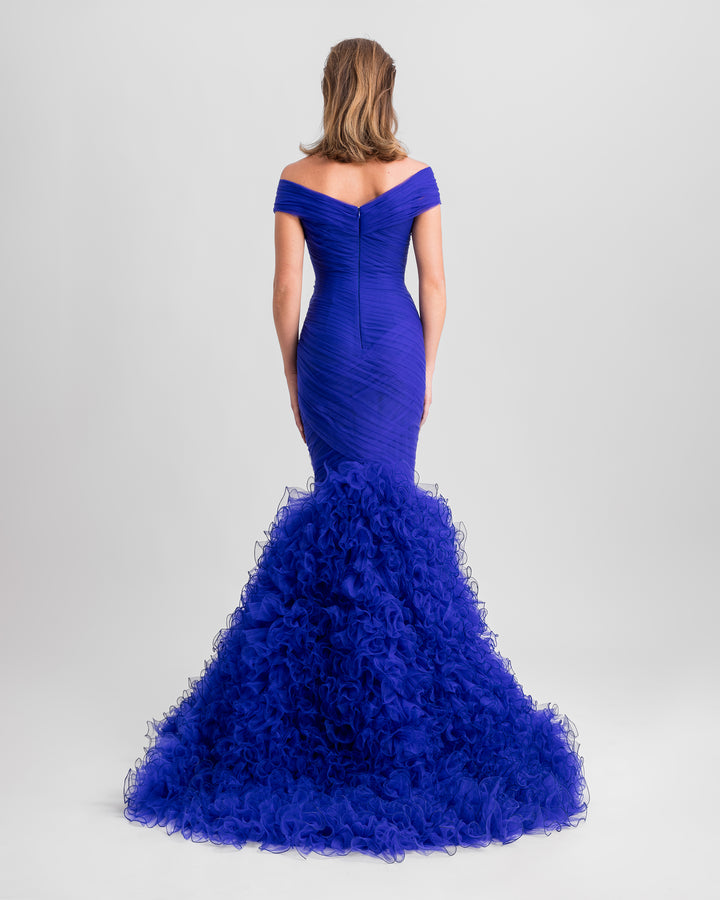 The back of an off-the-shoulders draped mermaid-cut blue evening dress with rushed tulle at the bottom.