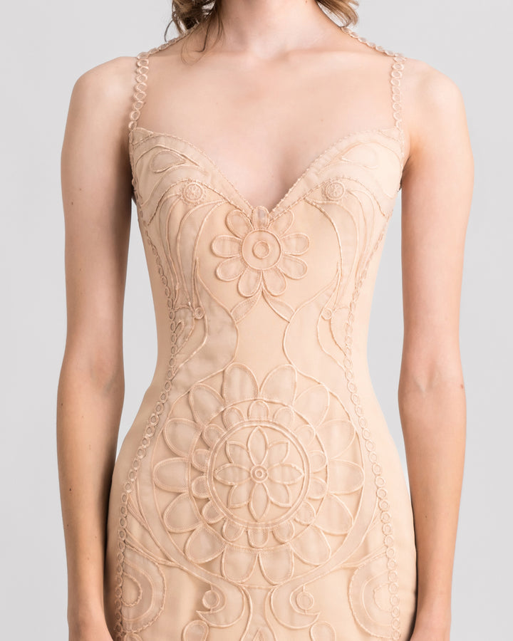 A close-up of a v-neckline, slim-cut lace evening dress in beige color.