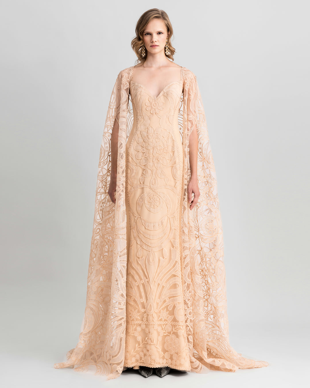 A v-neckline, slim-cut lace evening dress in beige color, paired with a wide lace cape.