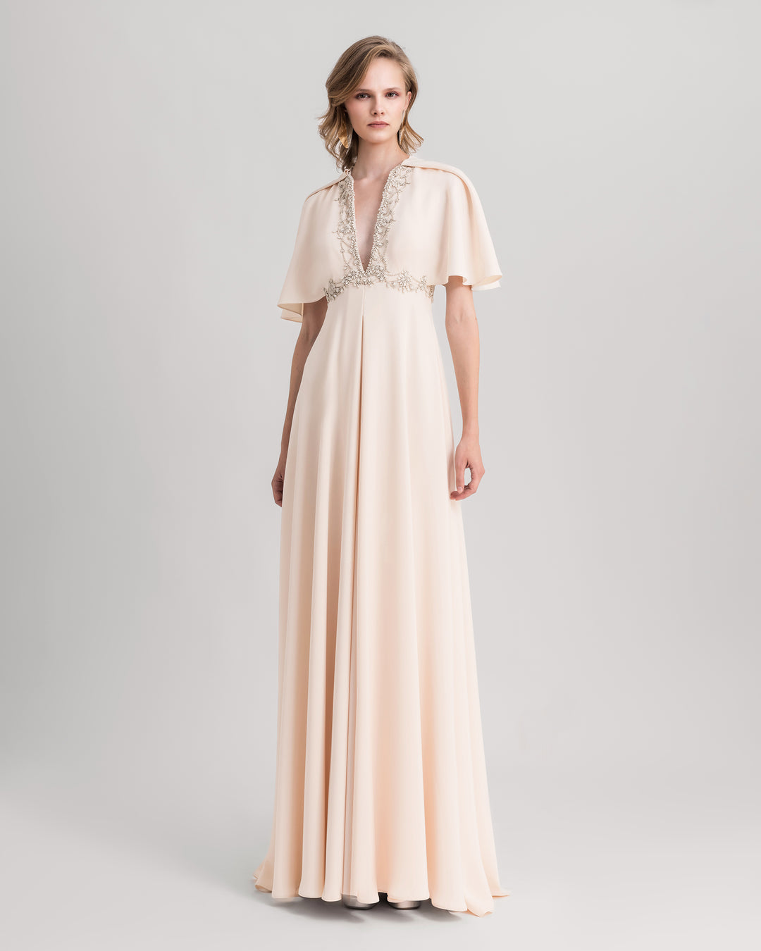 A deep beaded V-neckline evening dress in cream, featuring flared sleeves.