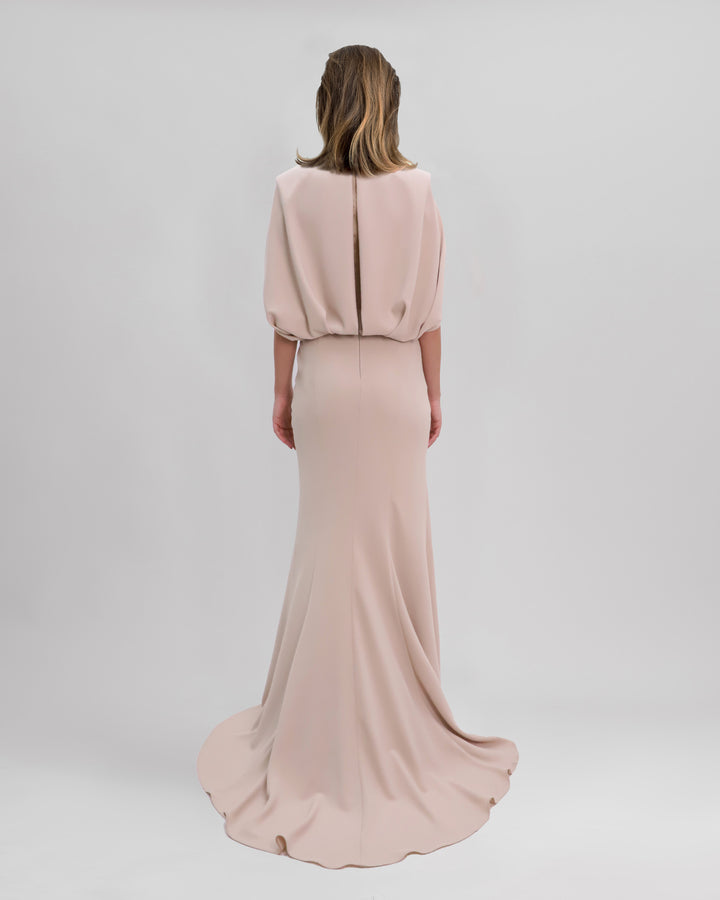 The back of a long slim-cut beige evening dress with cape like sleeves.