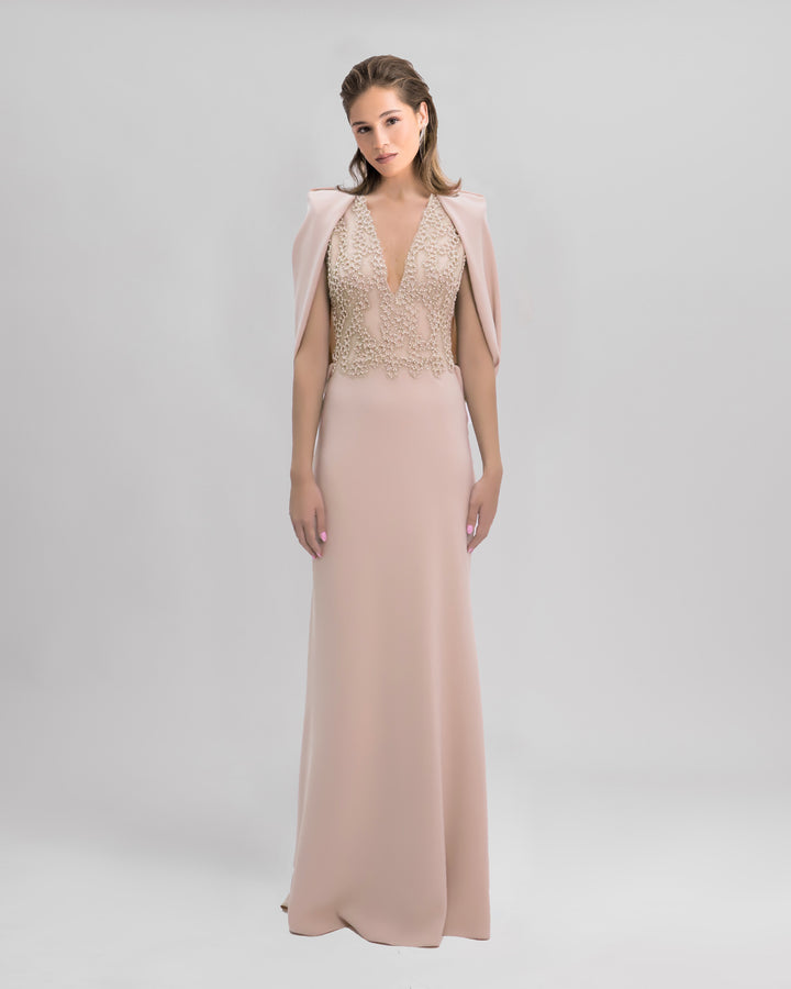 A long slim-cut beige evening dress with embroidered bodice and cape like sleeves.