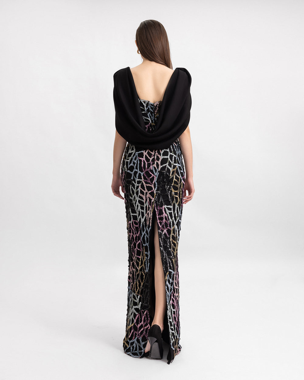 The back of a slim-cut beaded evening dress with draped crepe cape-like sleeves and a slit at the back.