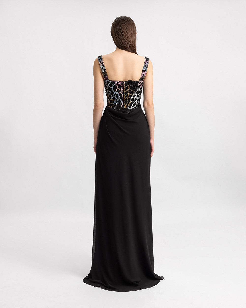 The back of a long black evening dress with draping on the side and multicolor beading bodice.