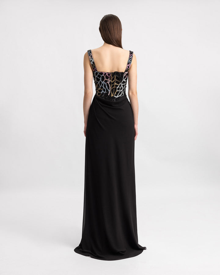 The back of a long black evening dress with draping on the side and multicolor beading bodice.