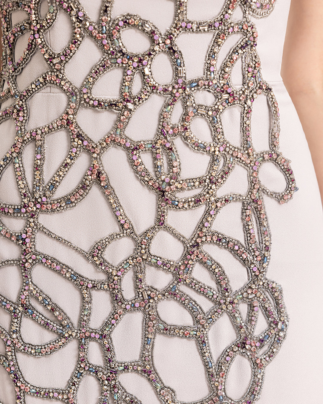 A close-up of a slim-cut evening dress with asymmetrical beading details.