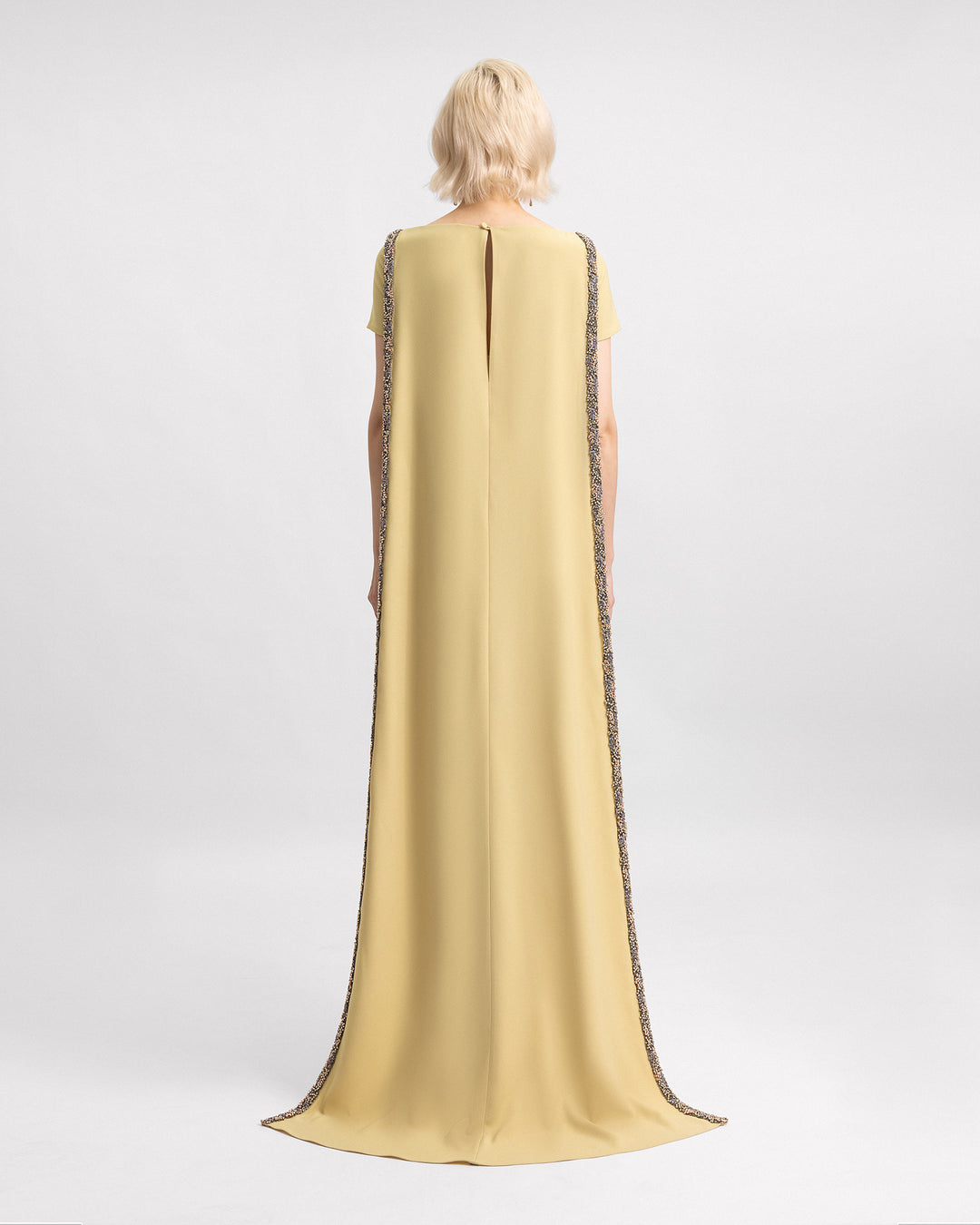 The back of beaded cape evening dress in golden mustard color.