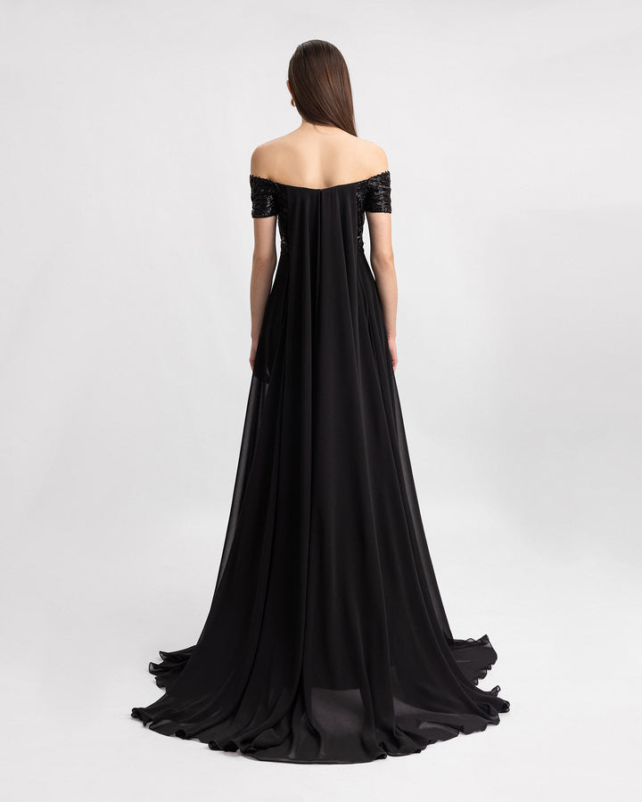 The back of a beaded off-the-shoulders black evening dress with long gathered chiffon tail.