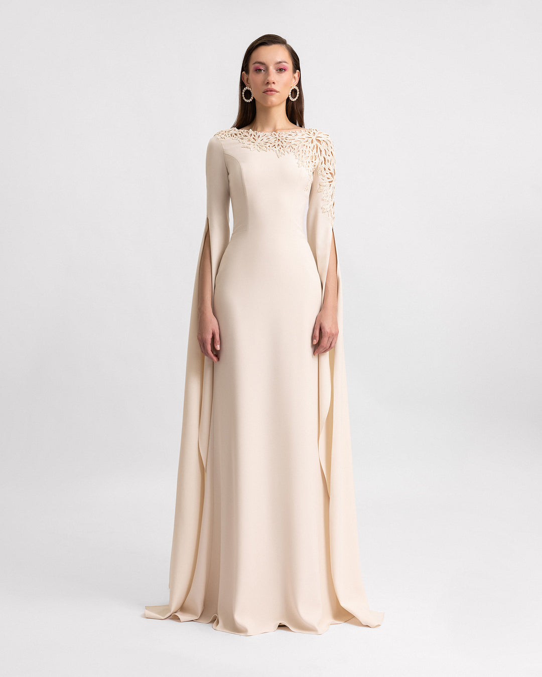 A slim-cut evening dress in champagne color with beadings on the neckline and floor-length sleeves.