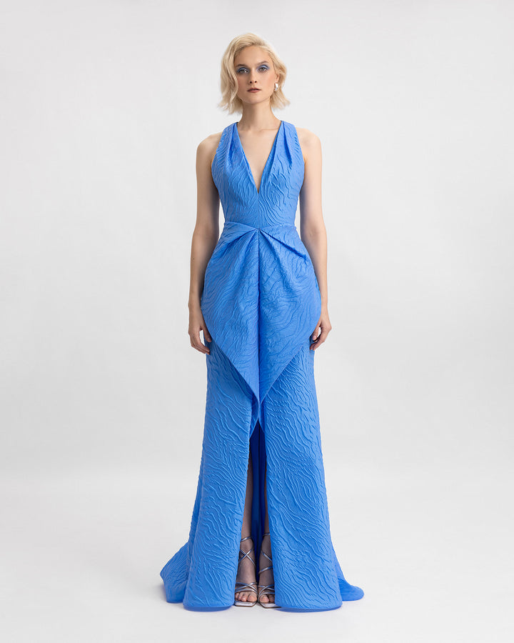 A blue v-neckline evening dress with a draped waistline and a slit in the middle.