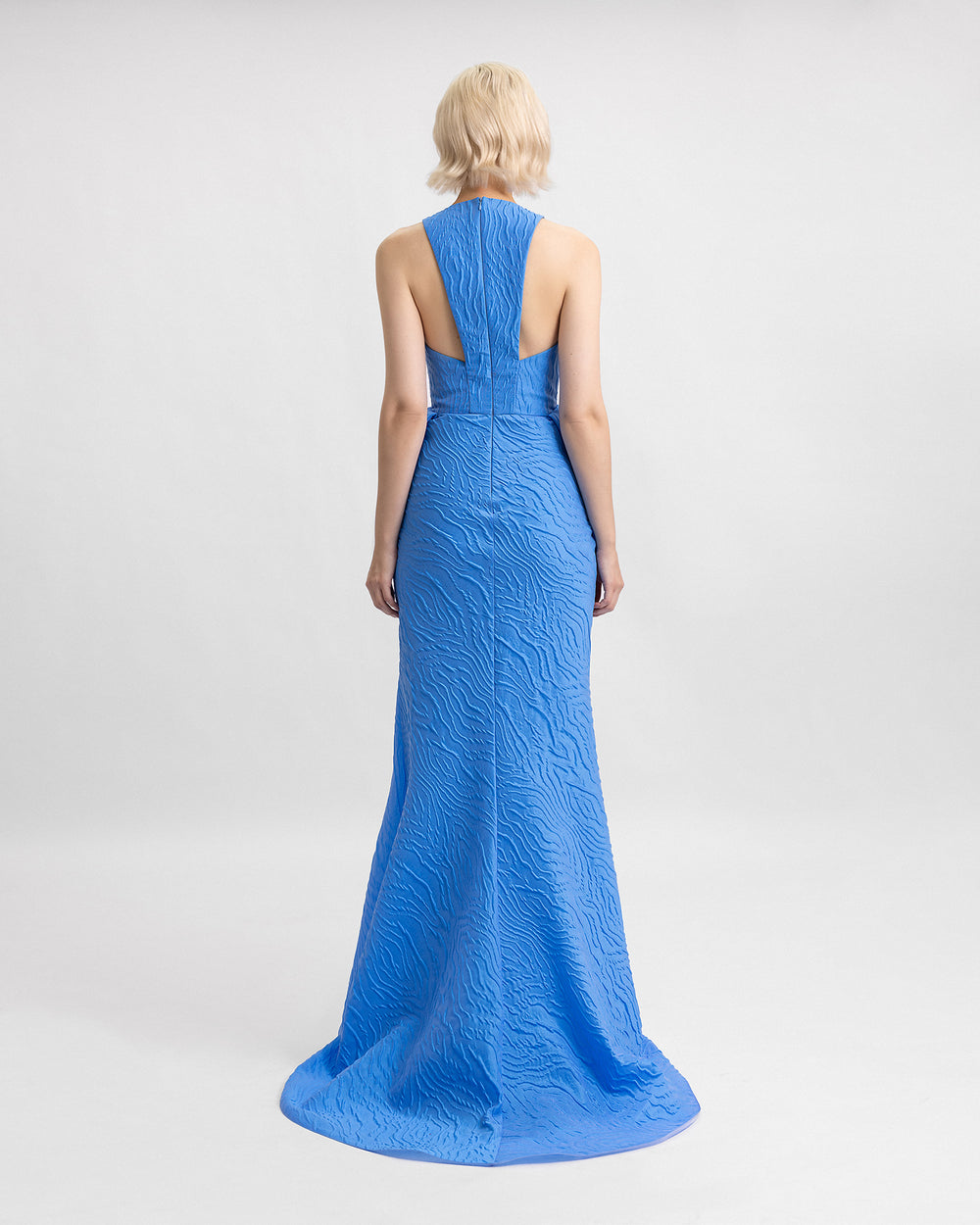 The back of a blue evening dress with a draped waistline and back cut outs.