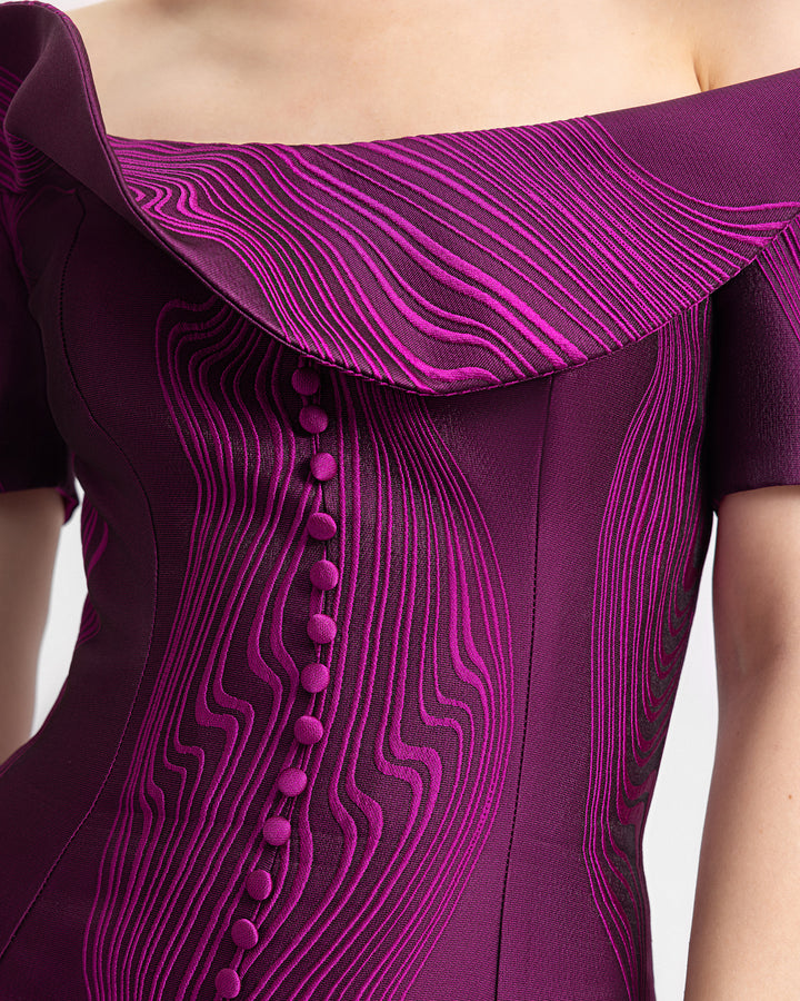 A close-up of a draped off-the-shoulders slim-cut evening dress in mulberry jacquard fabric with a buttoned down front.