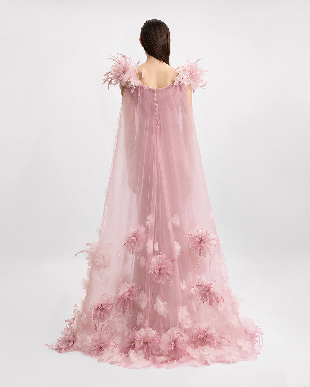 The back of a slim-cut pink evening dress with a long organza 3D floral cape.