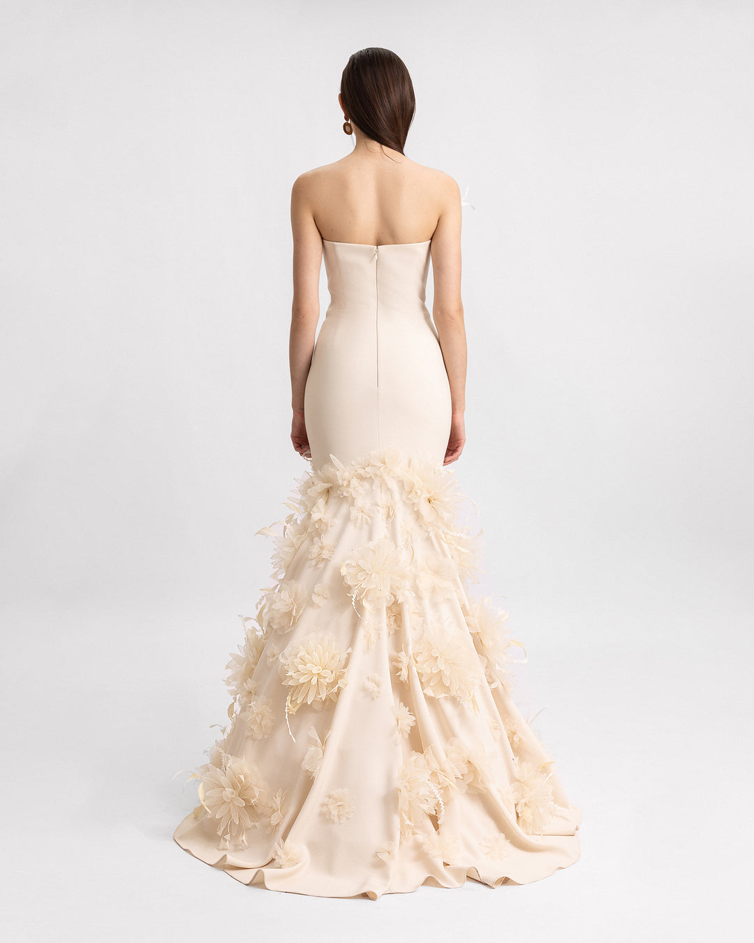 The back of a mermaid-cut strapless evening dress in champagne color with 3D flower details.