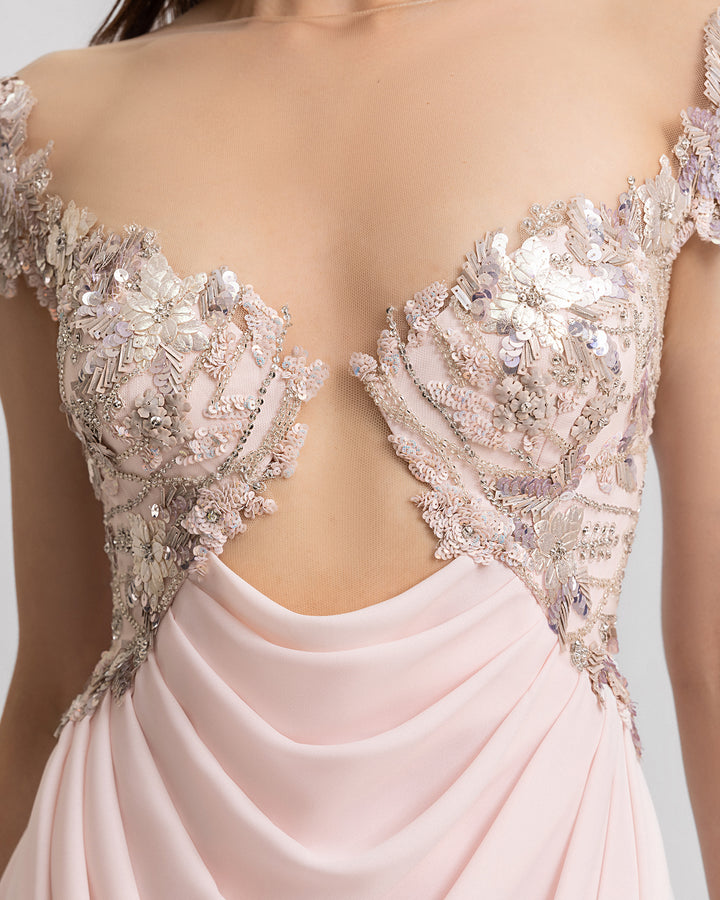 A close-up of a long pink evening dress with a cut-out beaded corset and a draped crepe georgette skirt.