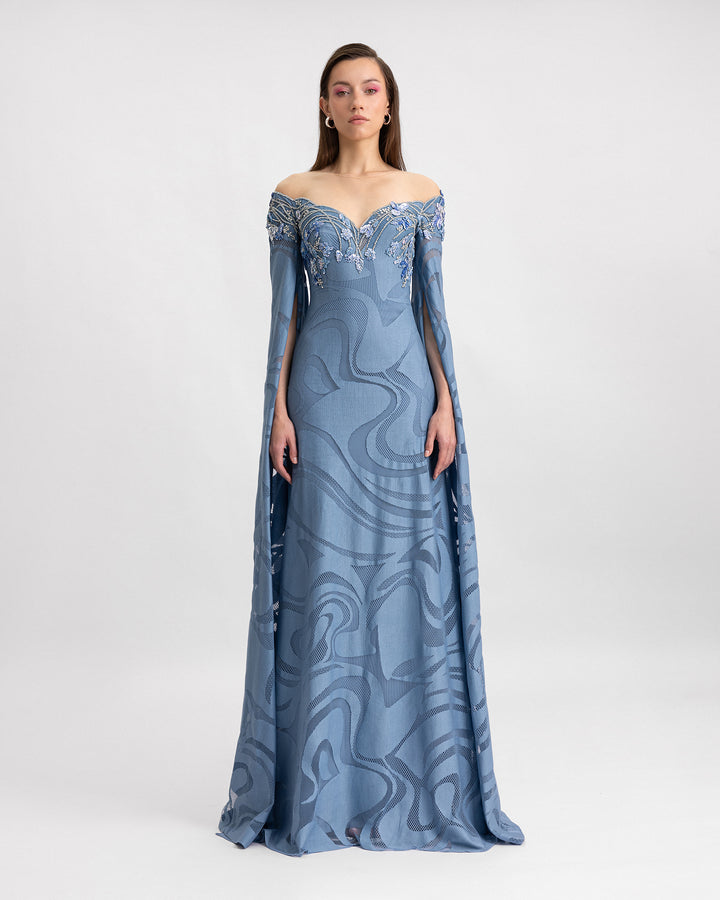 An off-the-shoulders lace evening dress in blue color with a beaded neckline and floor-length sleeves.