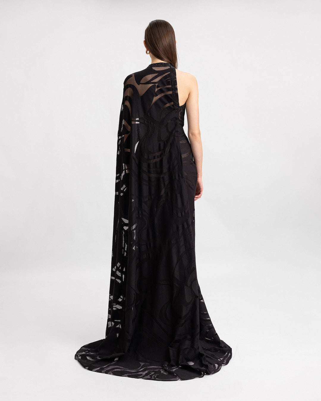 There back of an asymmetrical neckline black evening dress with a floor-length sleeve and beading details on the corset.