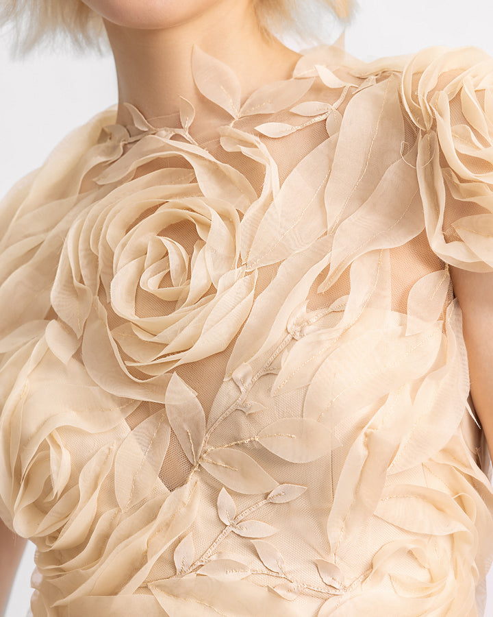 A close-up of a long champagne evening dress with a floral embroidered corset and a silk chiffon flowy skirt.