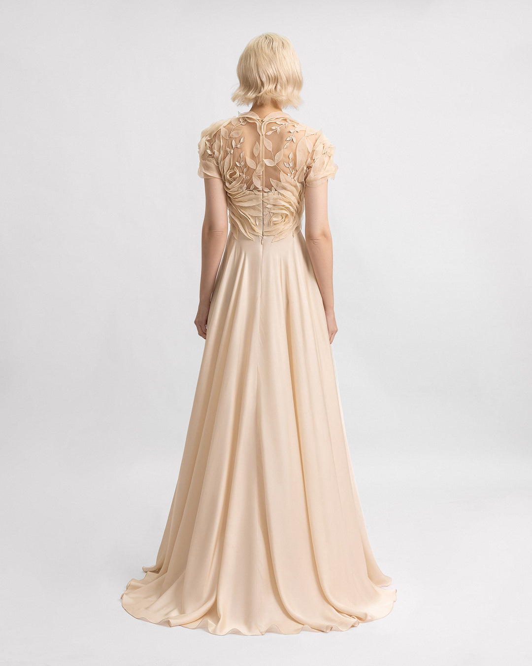 The back of a a long champagne evening dress with a floral embroidered corset and a silk chiffon flowy skirt.