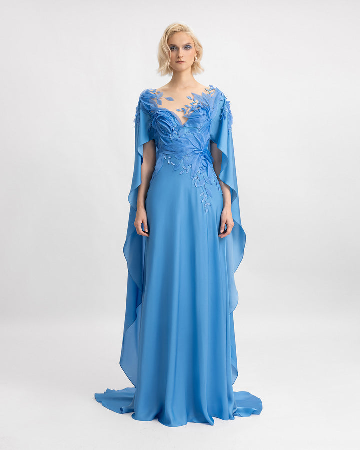 A v-neckline silk chiffon dress in blue color with floral embroidered organza details and ruffled cape-like sleeves.