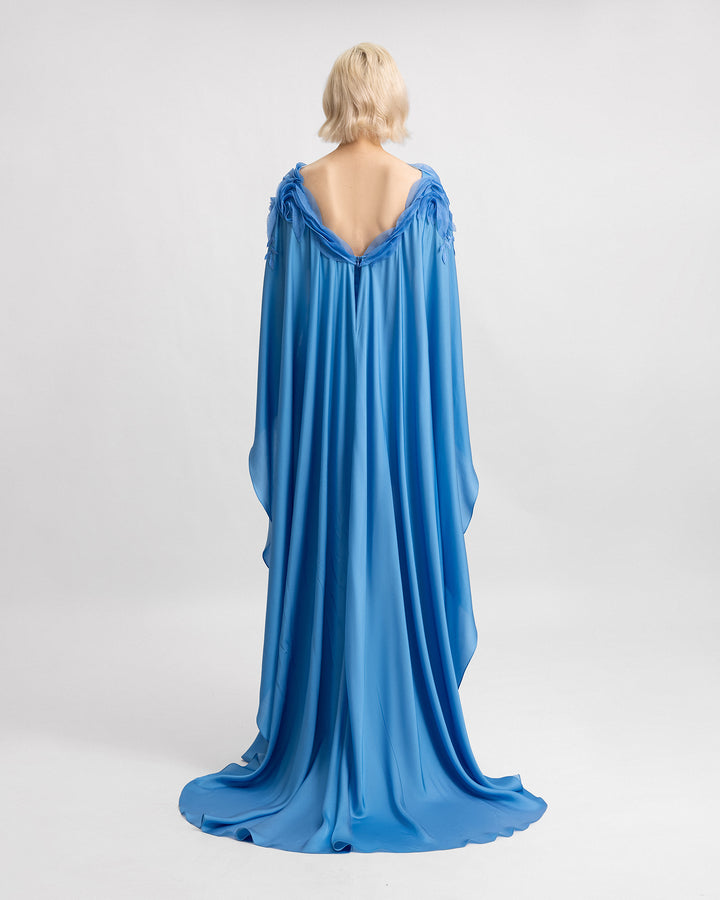 The back of a silk chiffon dress in blue color with floral embroidered organza details and cape-like sleeves.