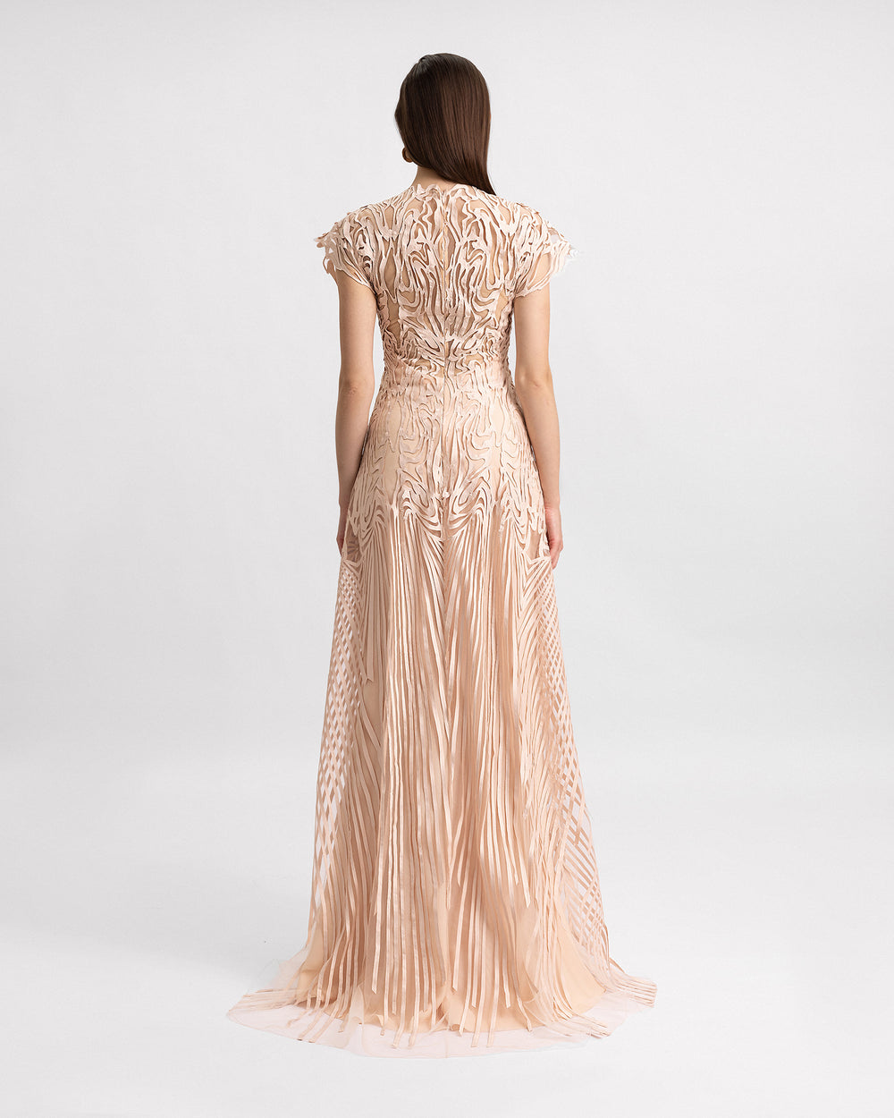 The back of a blush evening dress in embroidered laser-cut fabric featuring structured short sleeves.