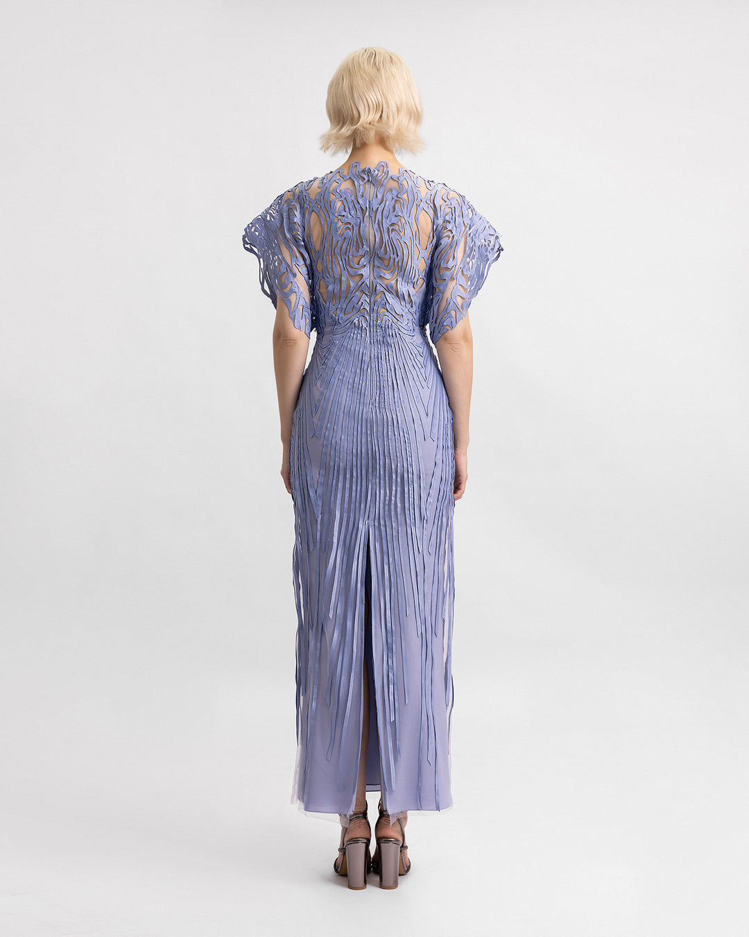 The back of a laser-cut embroidered evening dress in dusty blue with structured half-sleeves.