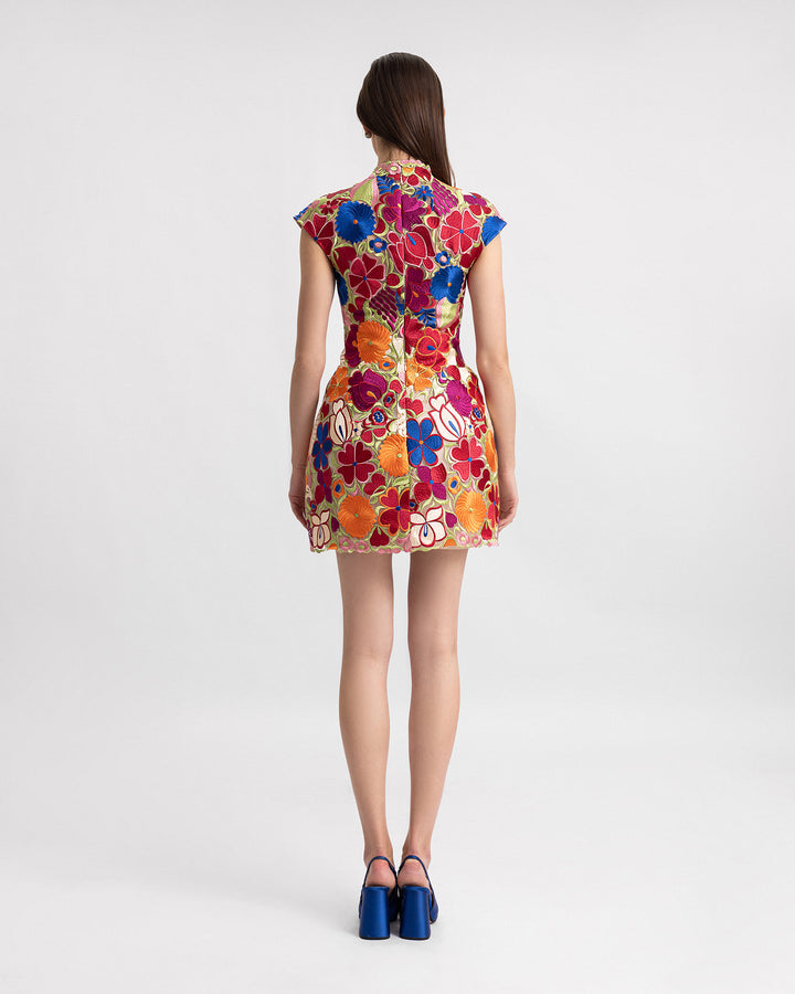 The back of a short structured evening dress in multicolor floral guipure fabric with cap sleeves.