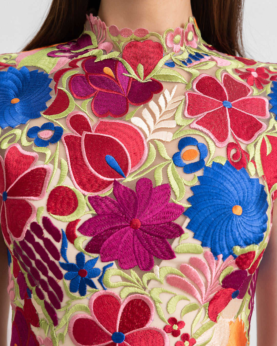 A close-up of a short structured evening dress in multicolor floral guipure fabric.