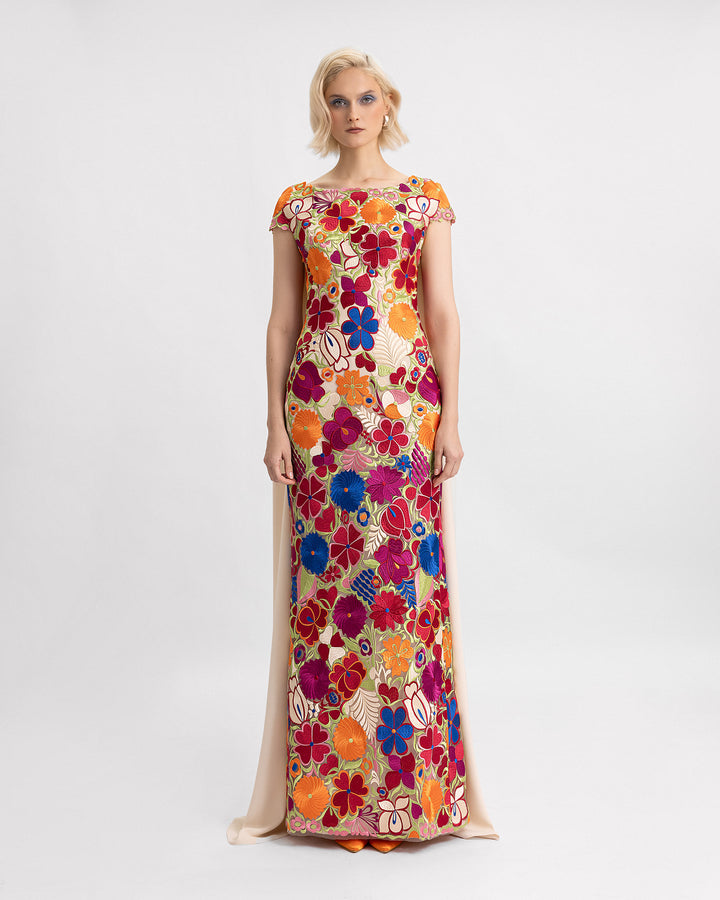 A slim-cut evening dress in multicolor floral guipure fabric with short sleeve and a long beige crepe cape.