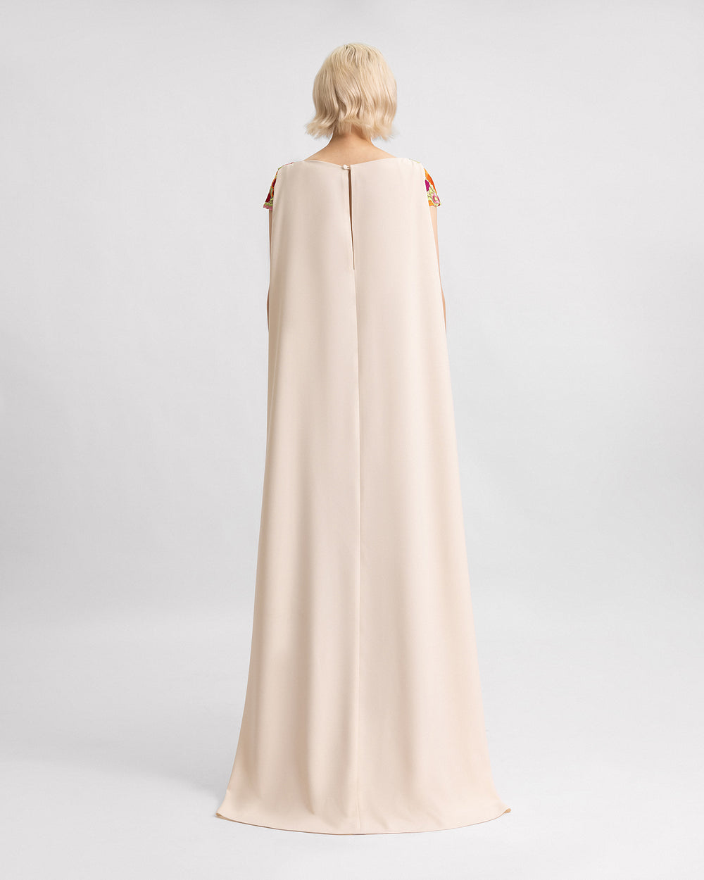 The back of an evening dress with a long beige crepe cape.