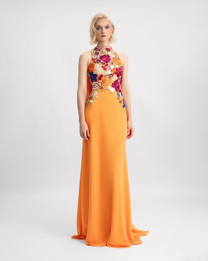 A halter-neckline evening dress with a multicolor floral guipure corset and a long orange crepe cape.