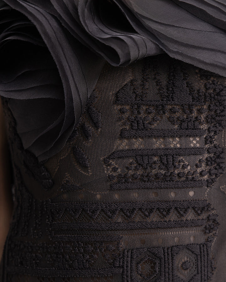 A close-up of a black lace evening dress with organza details.