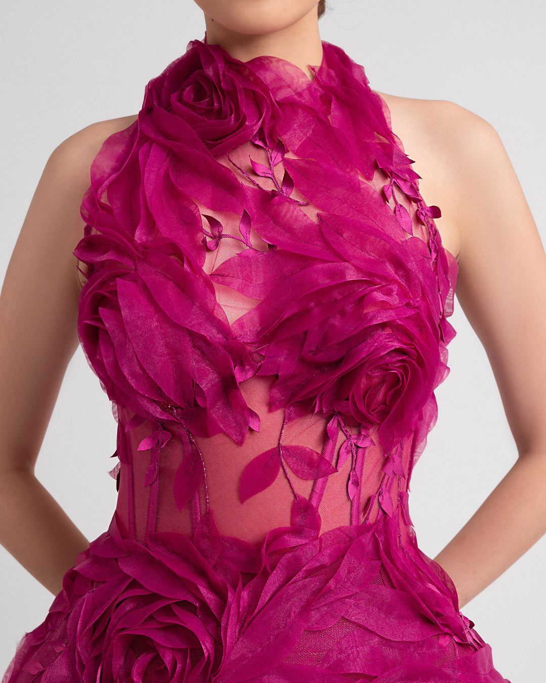 A close-up of a halter neckline evening dress with a fitted bodice adorned by organza floral appliqués.