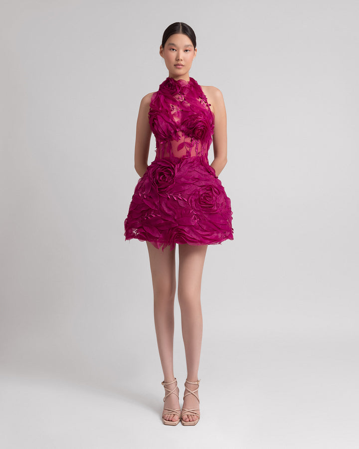 A halter neckline evening dress with a fitted bodice adorned by organza floral appliqués with a structured voluminous skirt.