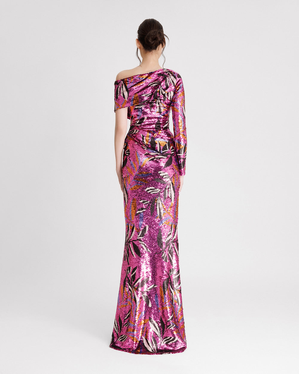 The back of a one sleeved asymmetrical neckline, slim-cut evening dress with draping on the waistline in a patterned sequins fabric.