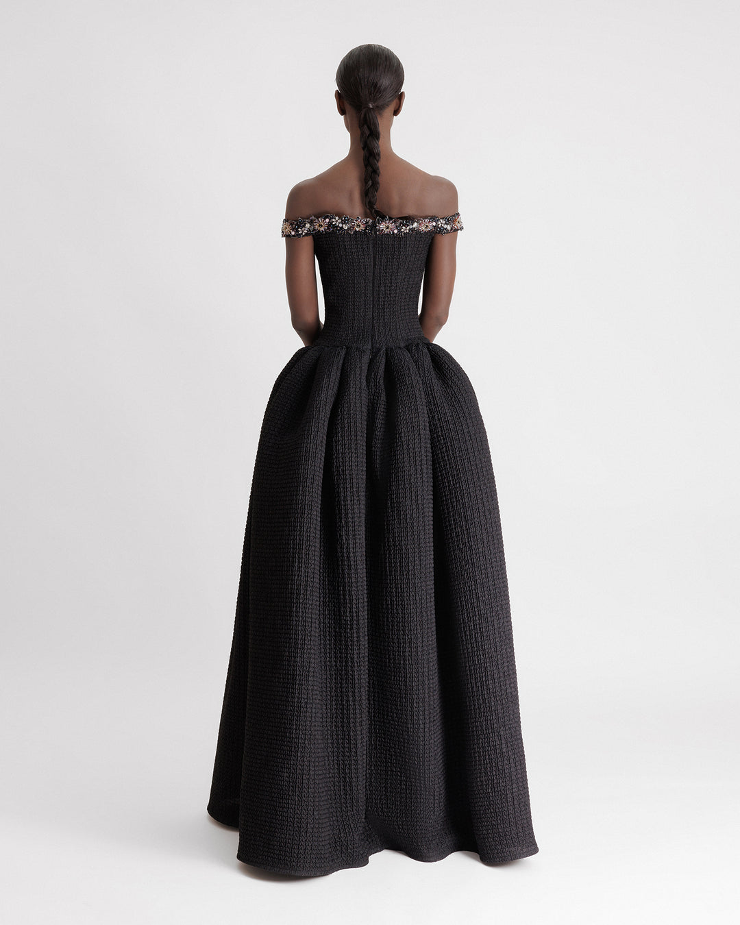 The back of a beaded off-the-shoulders dress with a dropped-down waistline and a draped skirt.