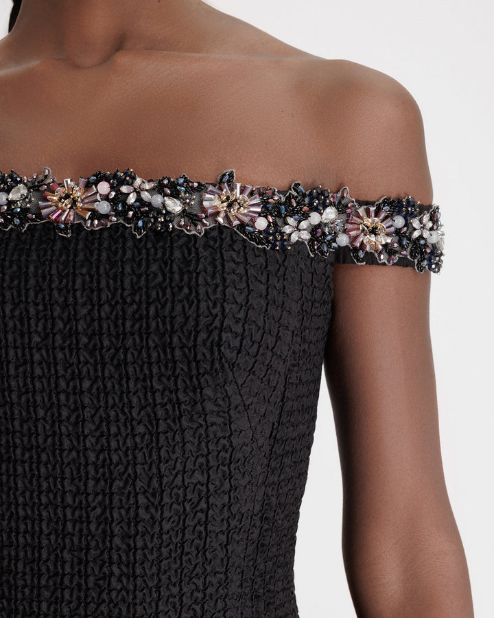 A close-up of a beaded off-the-shoulders black dress.