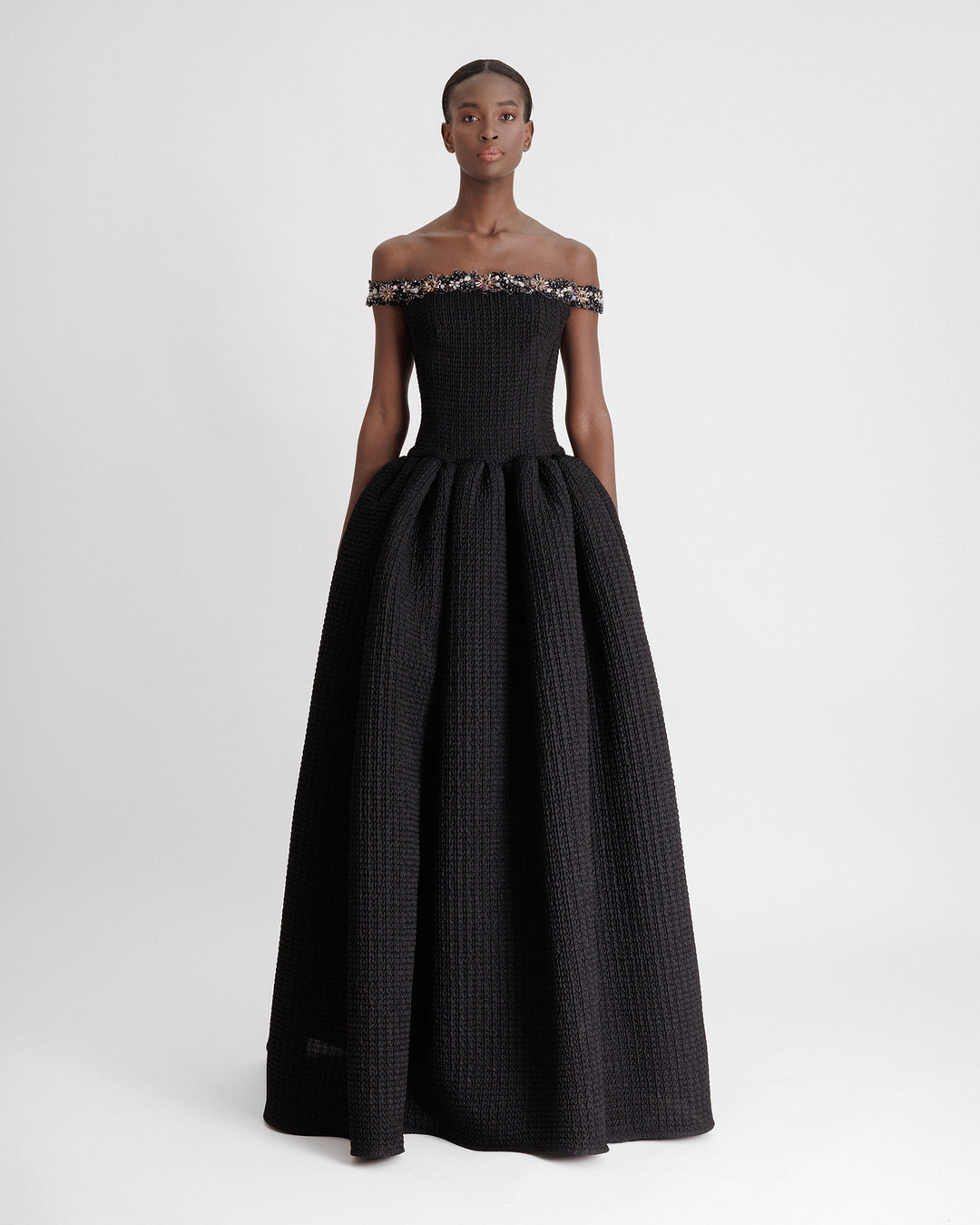 A beaded off-the-shoulders dress with a dropped-down waistline and a draped skirt.