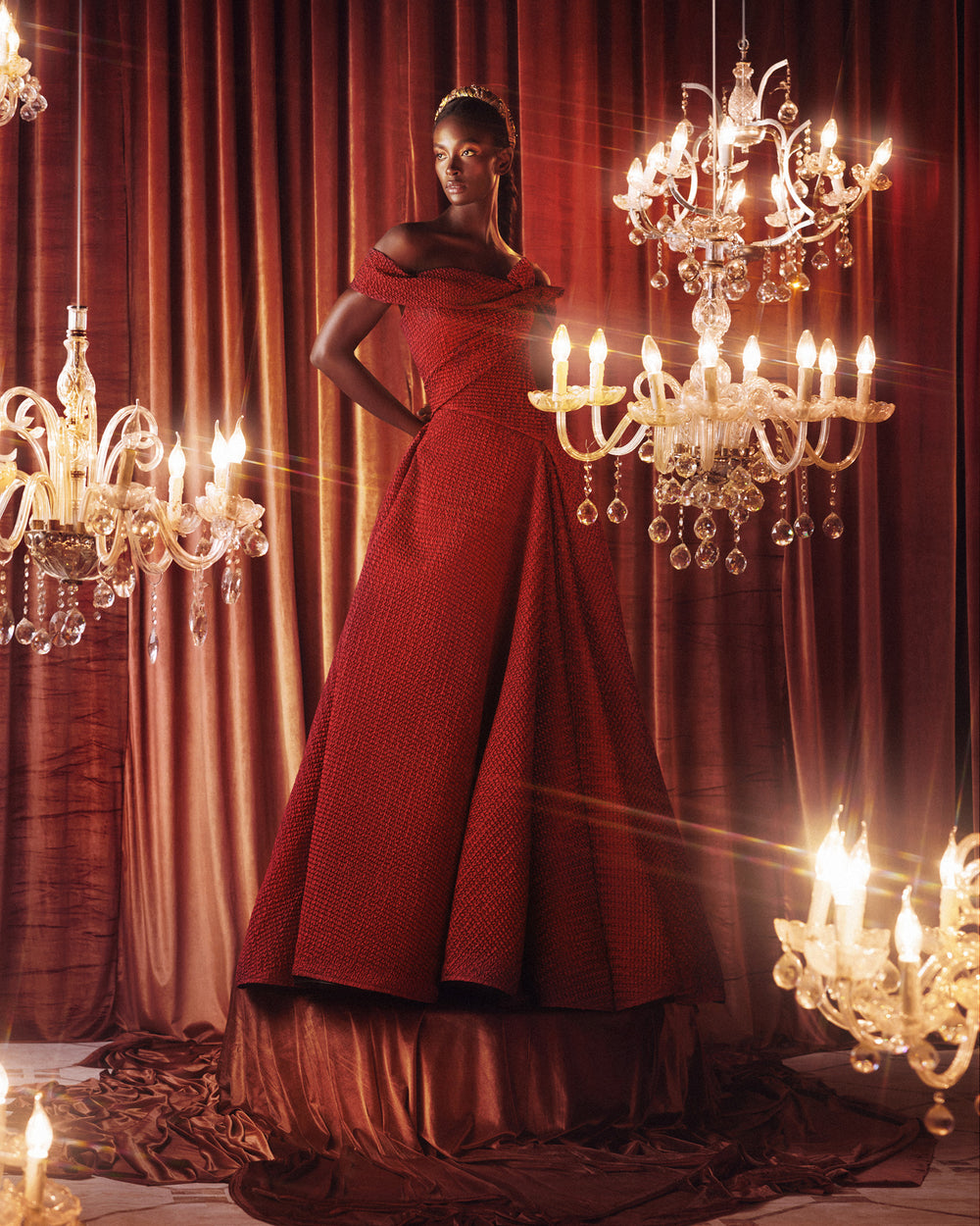 An off-the-shoulders red evening dress with an asymmetrical waistline and draped flared skirt.