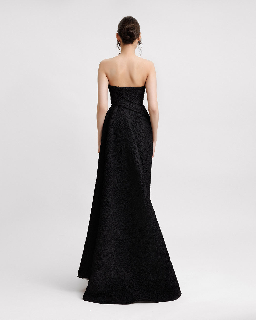 The back of a strapless black evening dress with a one-sided draped skirt.